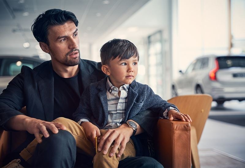 Man with boy on lap waiting for volvo maintenance